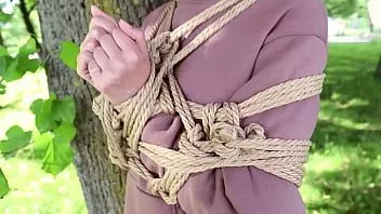 Riproduci Ragazza legata nel parco su uno sfondo di pietra